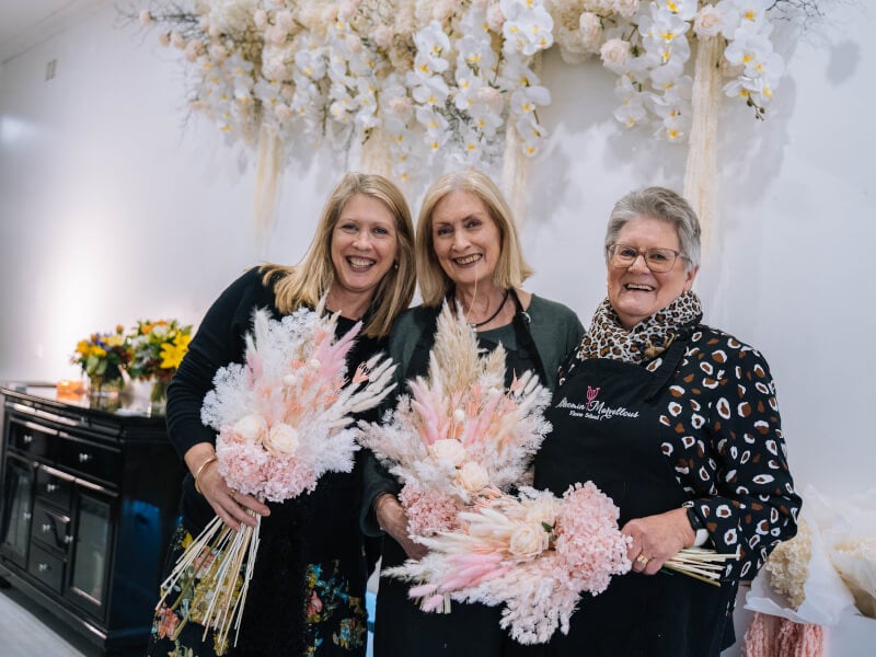 Three generations of women hold handmade bouquets for Mother's Day